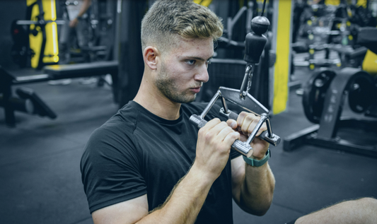 Athlète en salle de sport réalisant un exercice de préparation musculaire avant l'entraînement, échauffement des bras et des épaules pour réduire le risque de blessure et améliorer la performance.