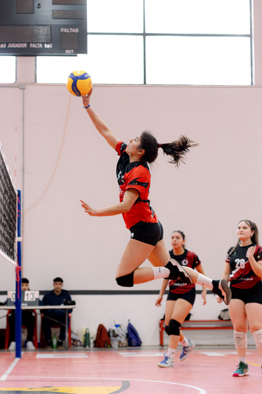 Joueuse de volley-ball réalisant un saut de frappe lors d'un match en intérieur 