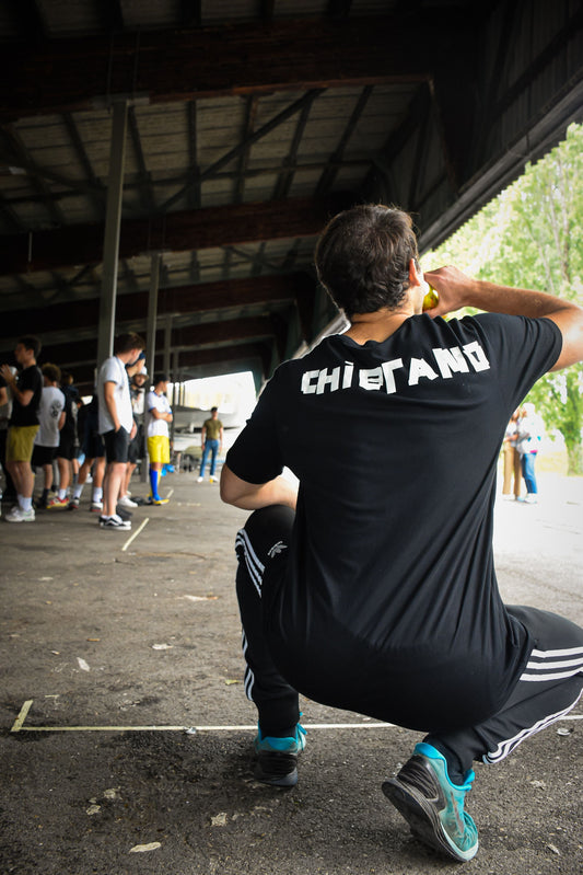 Un homme qui boit et fait une pause lors d'un événement sportif en plein air, illustrant le travail d'équipe et l'endurance.